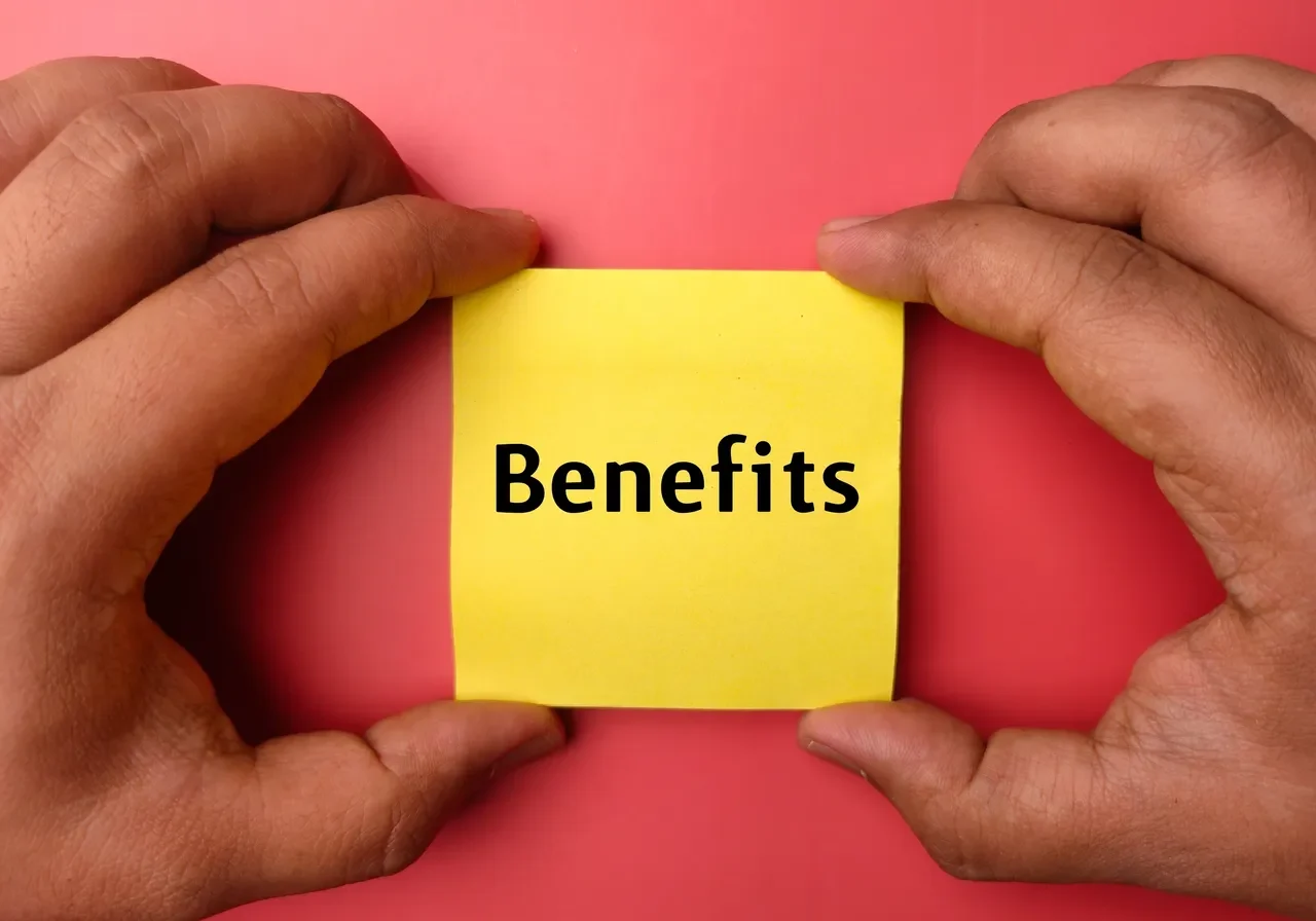 Hands holding "Benefits" sticky note
