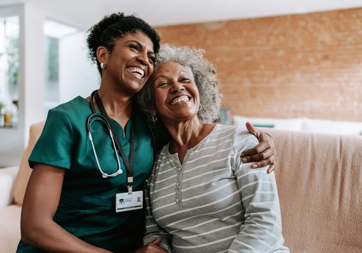 Caregiver hugging happy senior woman