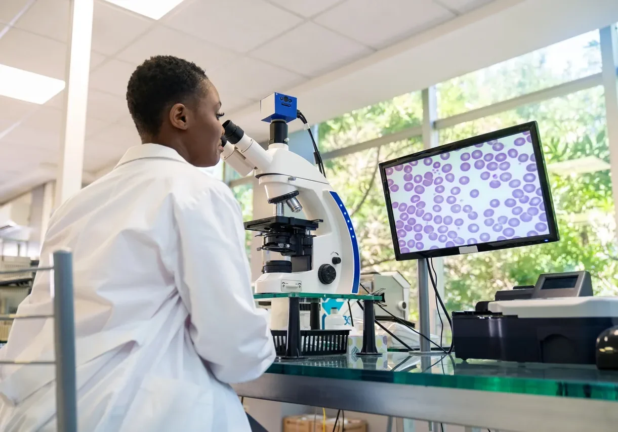Scientist examining samples under a microscope.